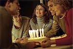 Friends gathered together presenting birthday cake to friend