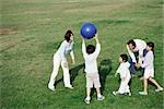 Family playing with ball in grassy field