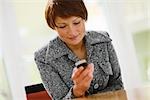 Businesswoman looking at cell phone, smiling