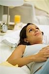 Pregnant woman lying on bed, daydreaming