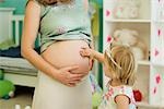 Kleines Mädchen berühren schwangeren Bauch der Mutter