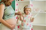 Pregnant woman playing with daughter in nursery