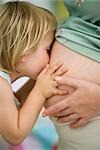 Petite fille embrassant le ventre de femme enceinte de mère