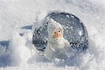 Boule à neige avec figurine de petite fille en vêtements d'hiver pour s'asseoir dans la neige