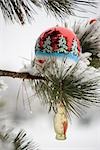 Christmas ornaments hanging on snow-covered branch