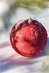 Red Christmas ornament on snowy ground