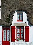 Extérieur d'un cottage au toit de chaume avec porte rouge et les volets de La Grande Brière, île de Fédrun, Pays de la Loire, France, Europe