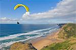 Paraglider with yellow wing above the south west coast of Portugal, Costa Vincentina, Praia do Castelejo and Cordama beaches near Vila do Bispo, Algarve, Portugal, Europe