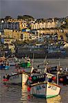 A stormy sky at sunset with small Cornish fishing boats in the harbour at St. Ives, Cornwall, England, United Kingdom, Europe