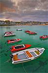Strange cloud formation in a stormy sky at sunset, with small red speedboats for hire with an incoming tide in the harbour at St. Ives, Cornwall, England, United Kingdom, Europe