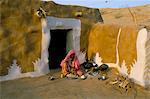 Woman cooking outside house with painted walls, village near Jaisalmer, Rajasthan state, India, Asia