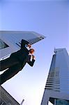 Business man with fingers in his ears in front of tall buildings