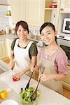 Women cooking food in kitchen and facing camera