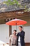 Front view of a middle-aged couple holding umbrella