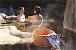 Couple relaxing in natural hot spring with wooden basket