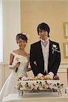 Bride and Groom debout derrière un gâteau