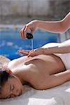 Massage therapist pouring oil