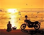 Silhouette de l'homme et de la moto au bord de la mer