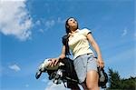 Young Asian female carrying golf bag