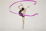 A teenage girl performing rhythmic gymnastics with leg raised