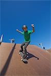 Jeune garçon plongeant avec planche à roulettes de skate park