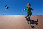 Jeune garçon plongeant avec planche à roulettes de skate park