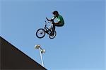 Mann mit Fahrrad gegen blauen Himmel springen