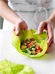 Woman Wrapping Chopped Avocado, Tomato and Cilantro in a Cabbage Leaf