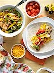 Fajitas au poulet avec poivrons verts et jaunes grillés, oignons, tomates et fromage Cheddar