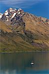 A tiny sail ship on the mountain edged Lake Wakatipu near Queenstown, Otago, South Island, New Zealand, Pacific