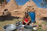 Local woman washing dishes in front of beehive houses built of brick and mud, Srouj village, Syria, Middle East