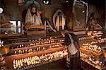 Vieilles lampes à beurre d'éclairage femme devant les statues de Bouddha drapées de nouvelles écharpes en soie, dans un petit temple, au stupa Boudha ou la Bodhnath, nouvel an tibétain (Lhosar), Katmandou, Népal, Asie