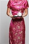 Cropped shot of woman wearing a pink cheongsam holding tea