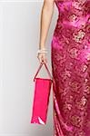 Cropped shot of woman in pink cheongsam holding shopping bag