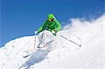 Man in green skiing off piste.