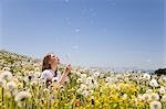 Girl in meadow blowing dandelion seeds