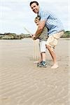 Vater und Sohn spielen Kricket am Strand