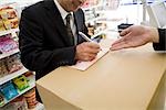 Customer at convenience store writing on slip