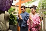 Young couple in kimono praying at Shinto shrine