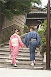 Young couple in kimono walking up stairs