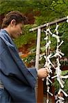 Young man in kimono knotting paper fortune