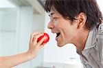 Father eating tomato from daughter's hand