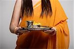 cropped shot of woman wearing a sari holding a tray with tea