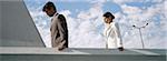 Businessman and businesswoman on rooftop, both looking down contemplatively