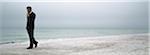 Man in suit walking on beach