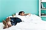 Homme couché sur le lit avec les bras derrière la tête