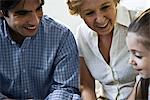 Father, grandmother smiling proudly at little girl