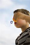 Little boy blowing bubble with bubble wand, low angle view