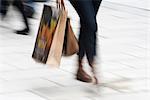 Pedestrian carrying shopping bags, low section, blurred