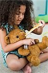 Little girl feeding teddy bear pizza